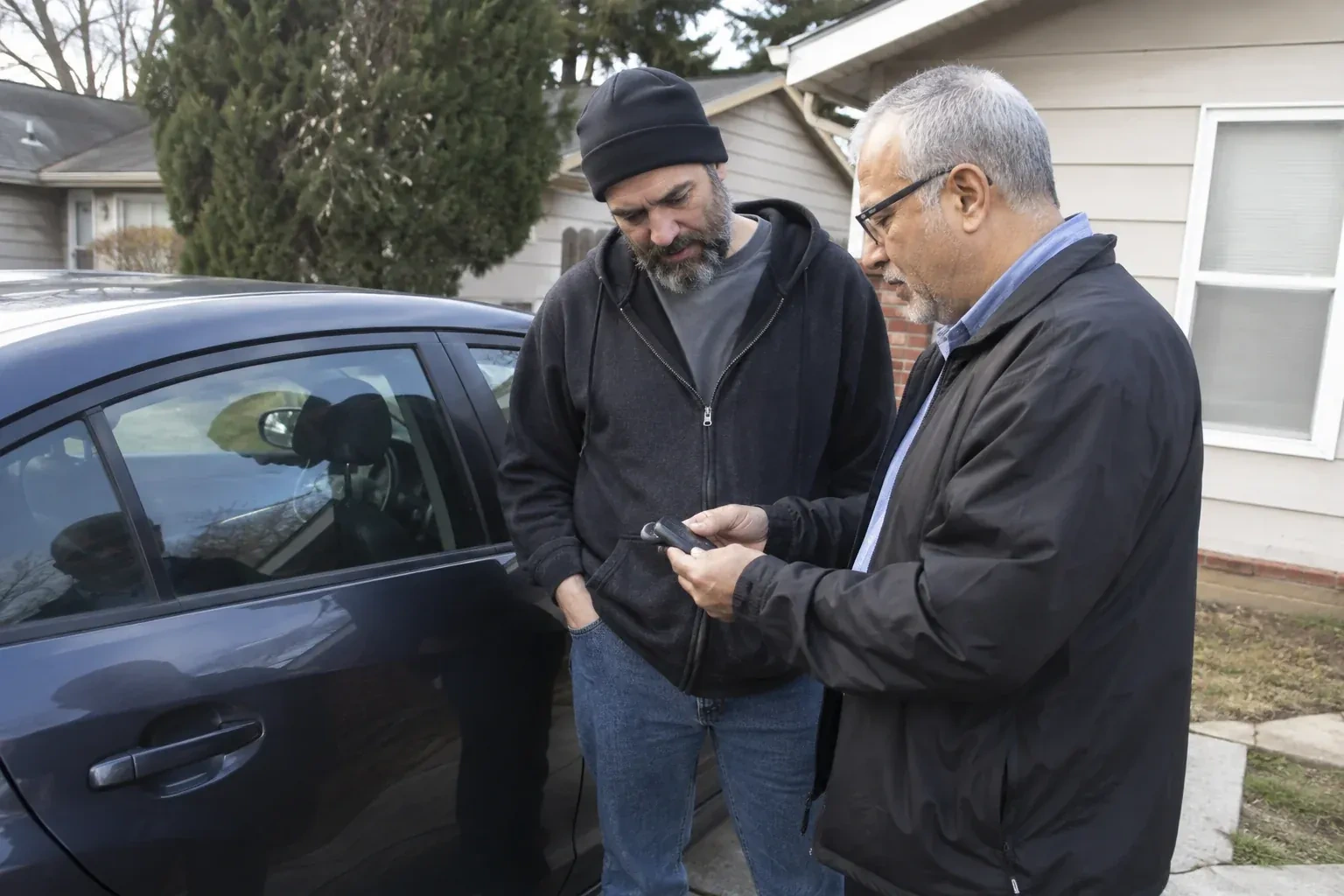 Two adults discussing a key fob beside a parked car. — Car Lockout Service, Wilmot